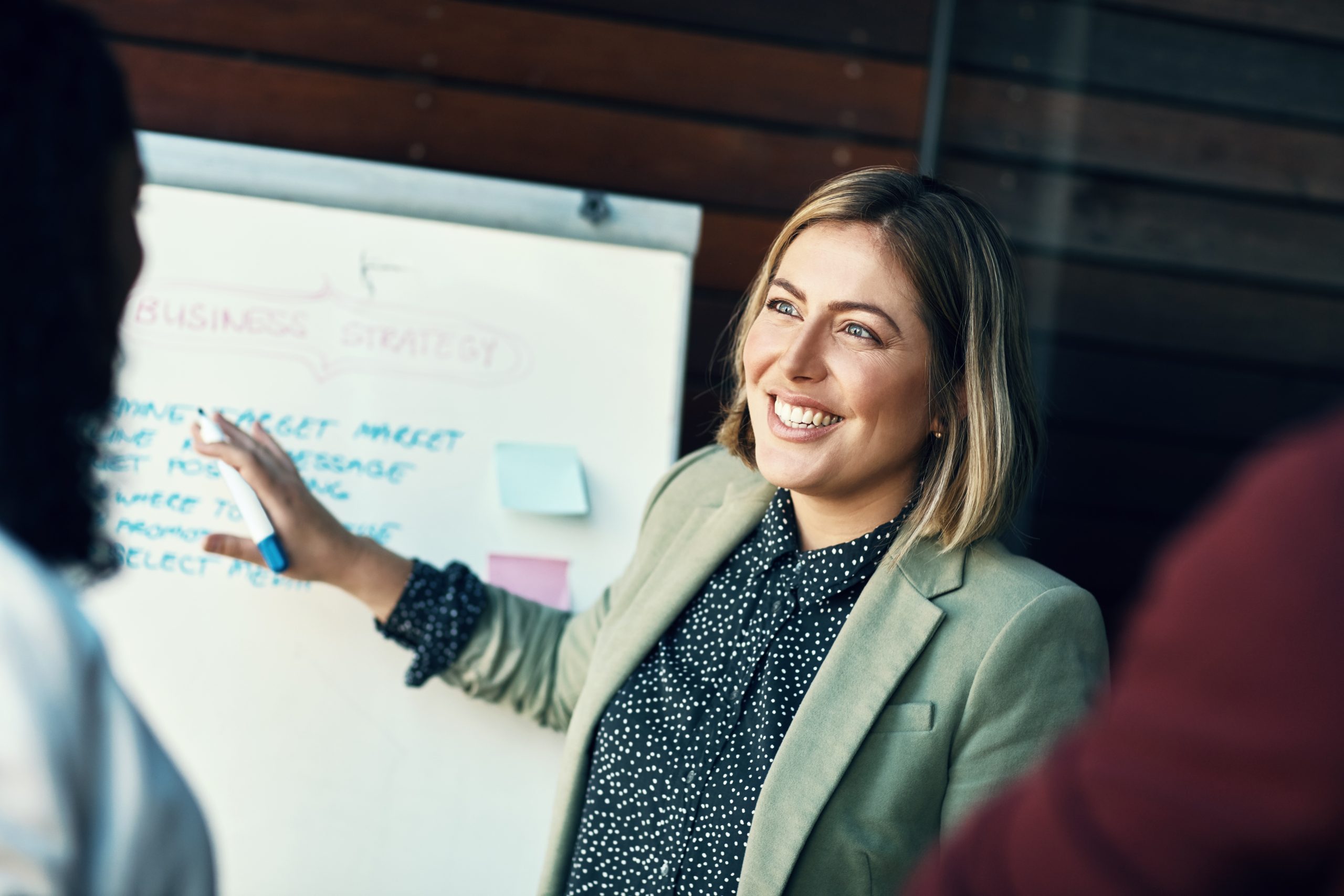 Presentation whiteboard, audience and happy woman planning, coaching and present strategy, ideas or office plan. Sales workshop, project management and team leader, boss or person speaking to group. coach